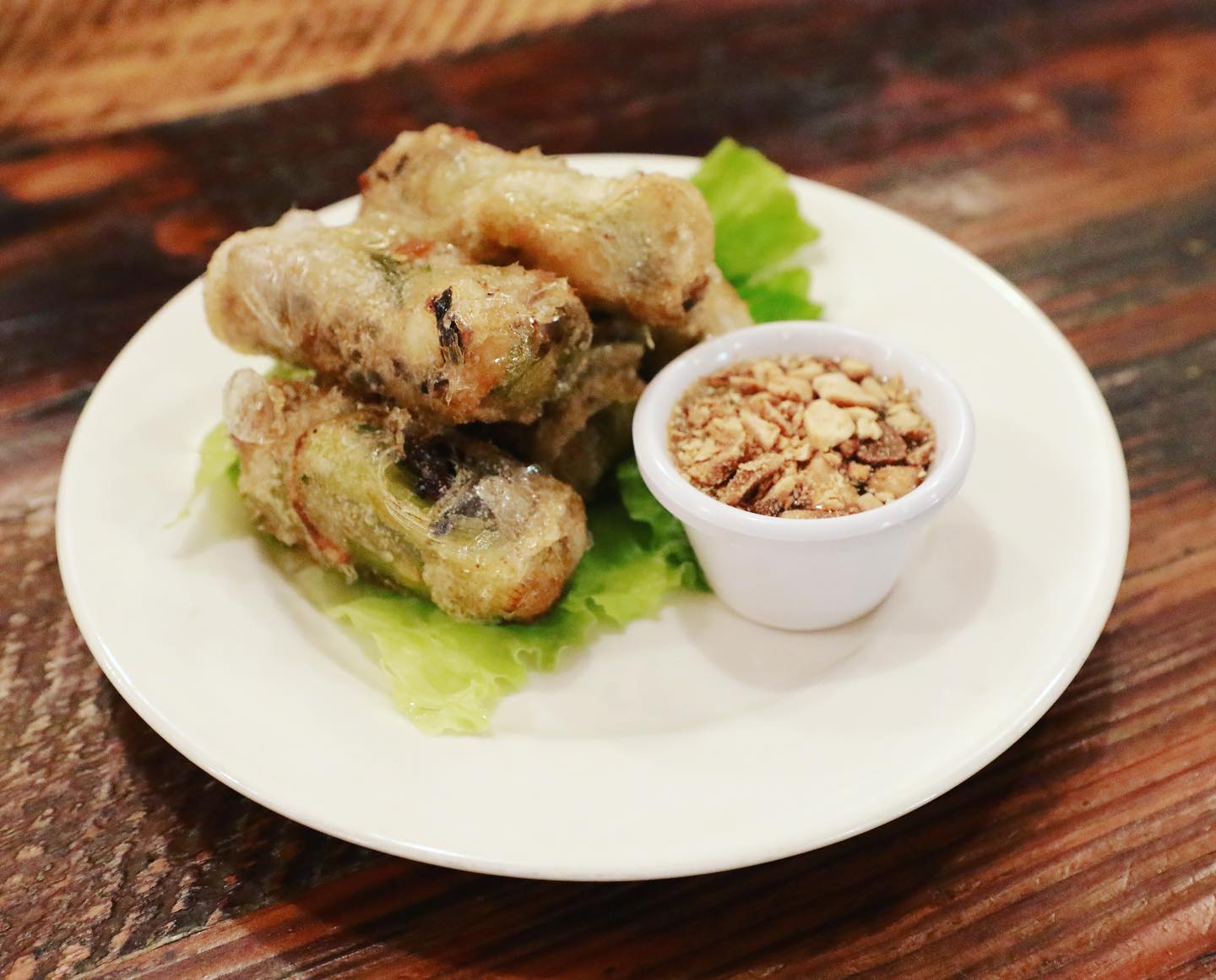 Traditional Hue-style chả ram fried spring rolls with translucent rice paper, shrimp and pork filling, served on lettuce with crushed peanuts at La Cà 38th in Tacoma